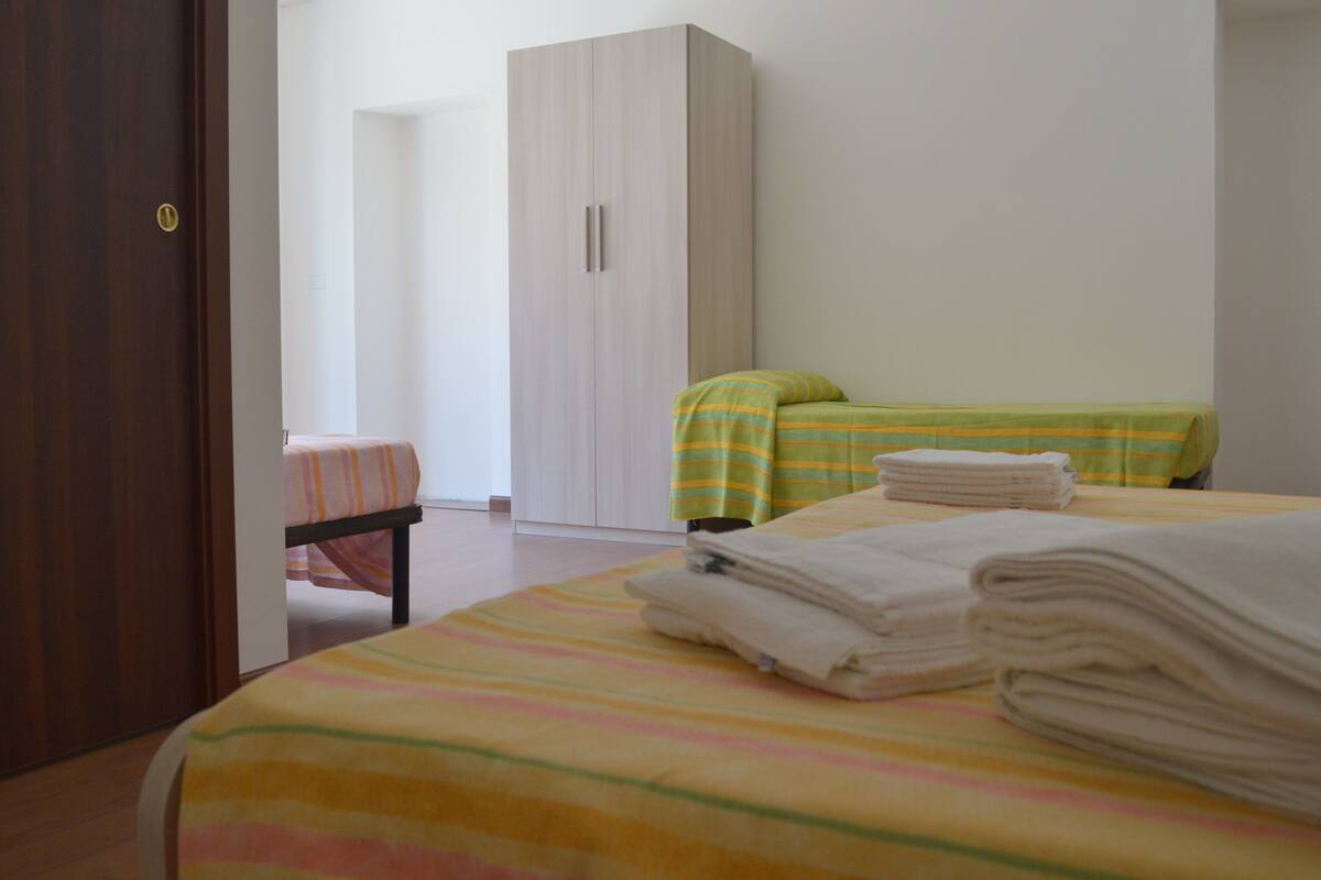 A bedroom with a bed, two bedside tables, a wardrobe, and a door.