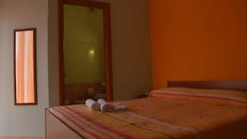 Une chambre d’hôtel avec un lit, un miroir et une fenêtre.
