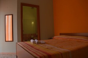 A hotel room with a bed, a mirror, and a window.