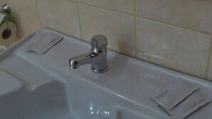 A bathroom with a white sink, a mirror, and a shelf above the sink. - B&B Scalea Rooms (Scalea)