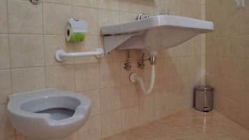 A bathroom with a toilet, sink, and trash can.