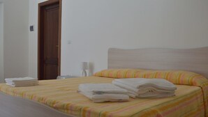 A hotel room with a bed, a wooden door, and a nightstand with a lamp. - B&B Scalea Rooms (Scalea)