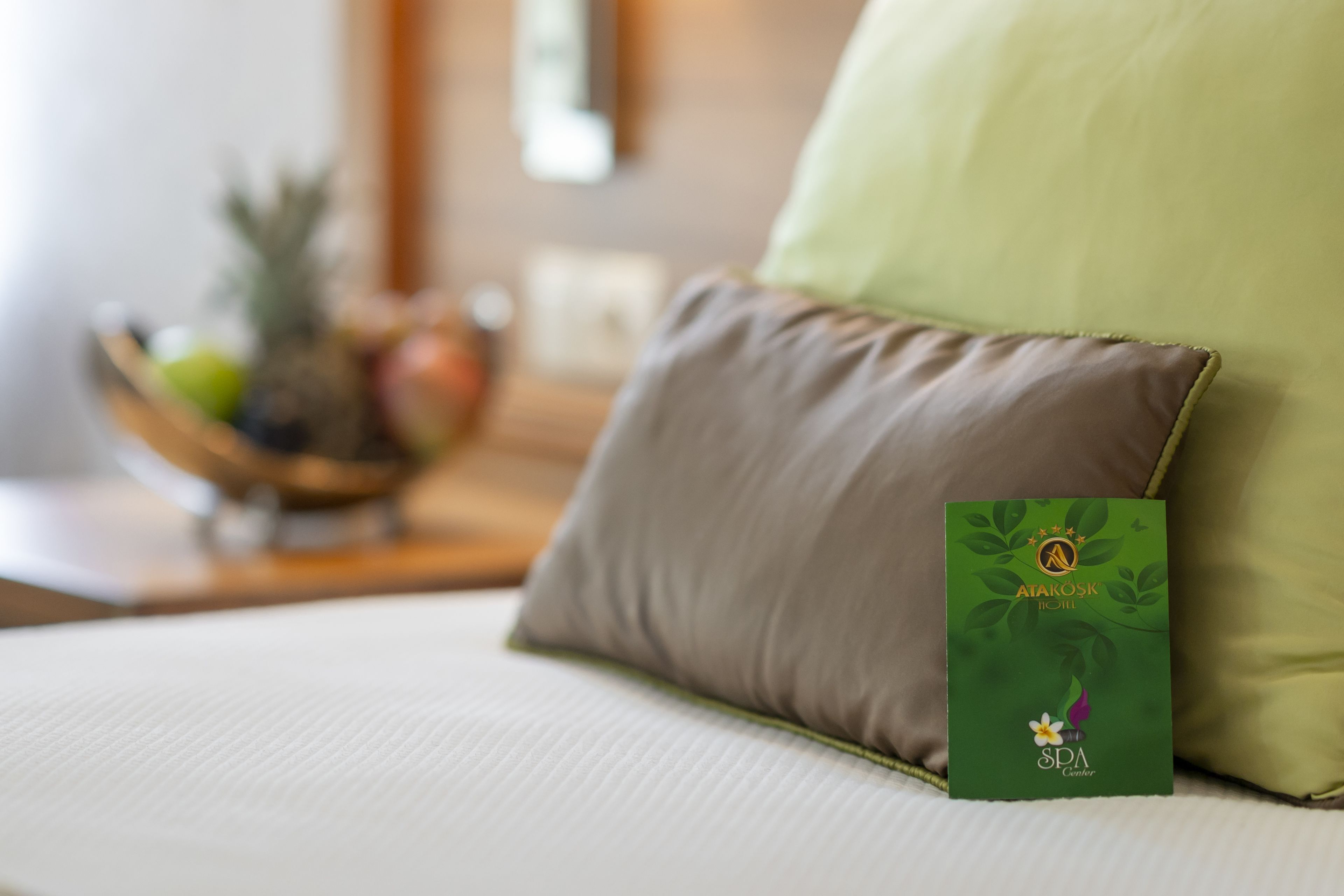 A bed with a green pillow and a spa center card on it.