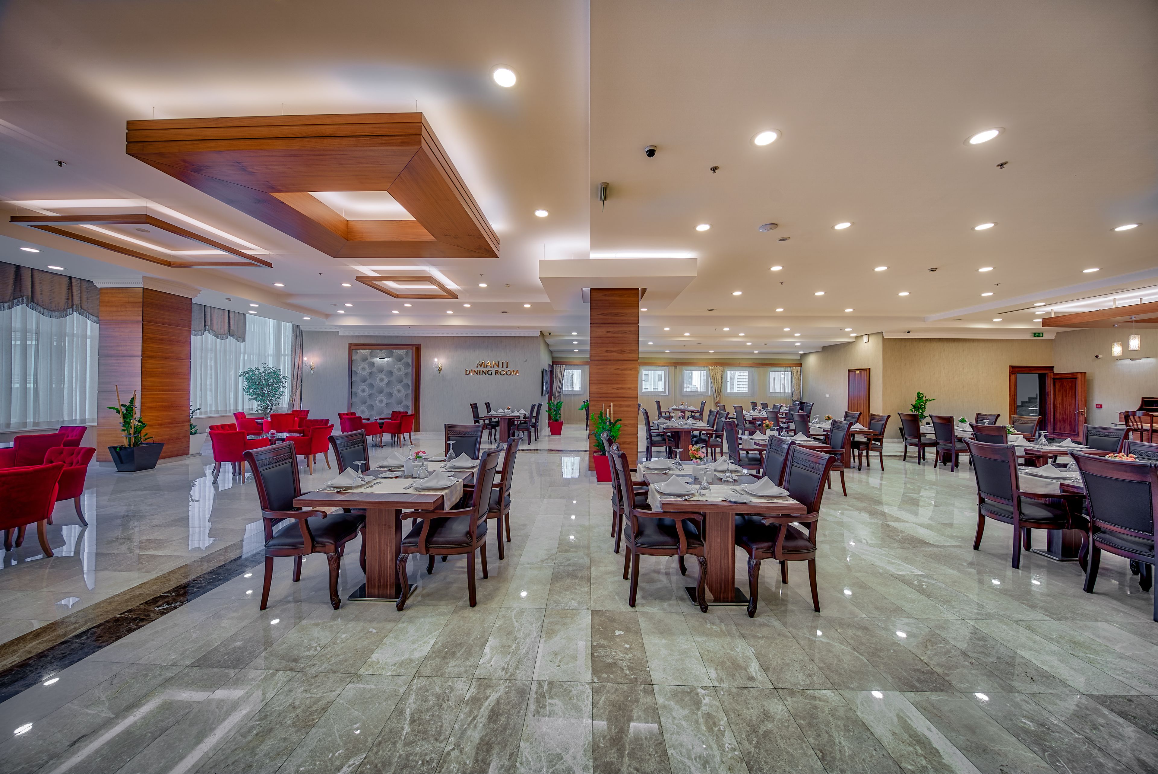 A spacious dining area with multiple tables and chairs, large windows, and ceiling lights.