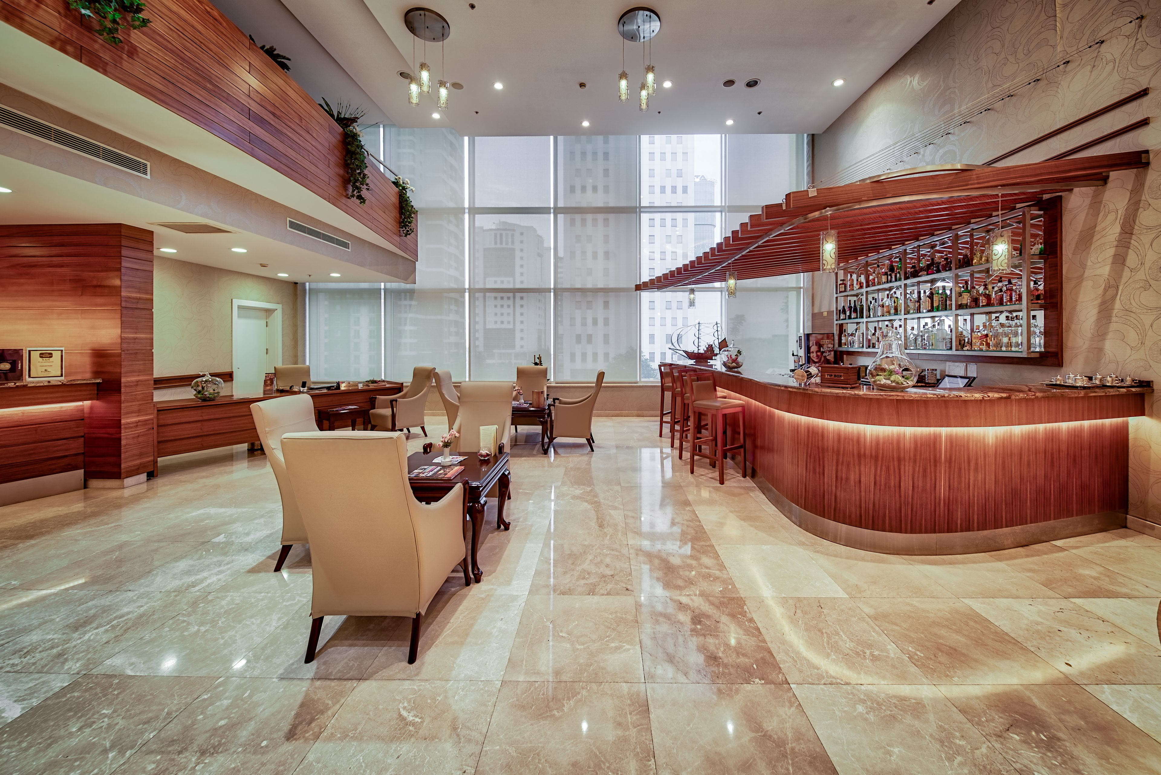 A spacious lobby with a curved reception desk, seating area, and large windows offering city views.