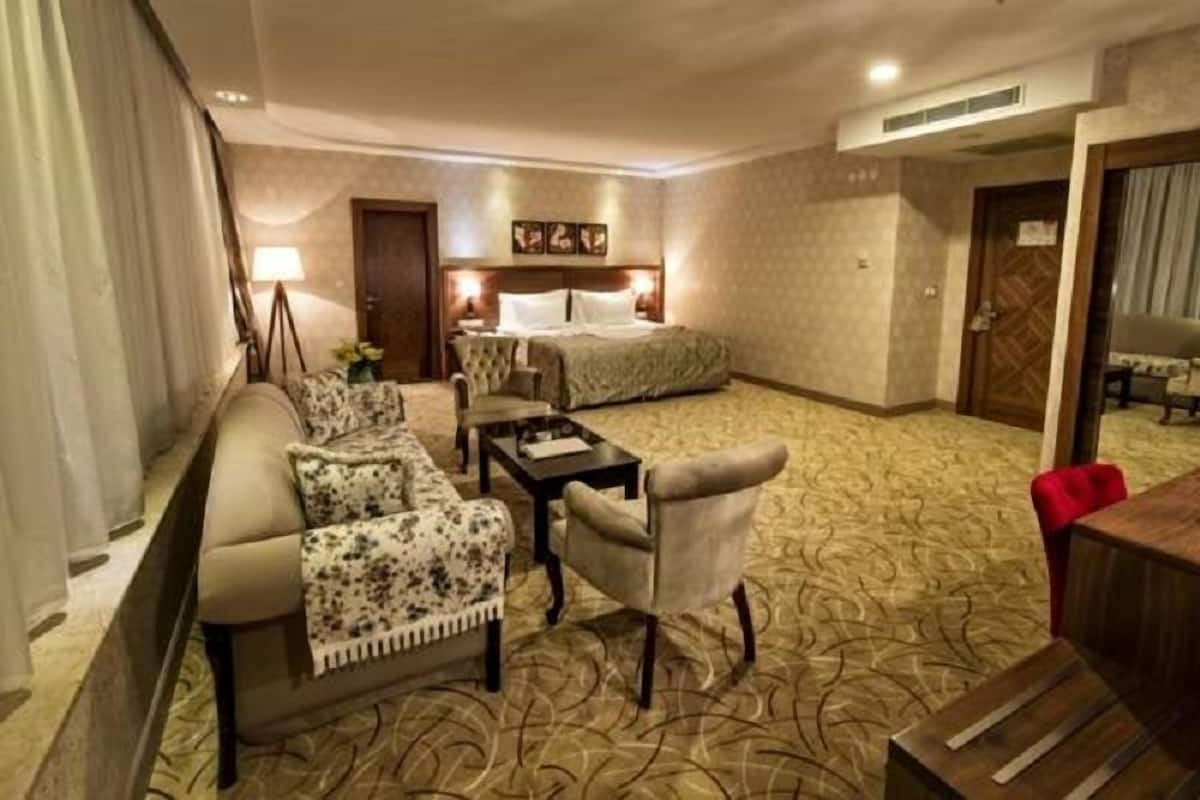 Una habitación de hotel con cama, sofá, sillón, mesa y escritorio.