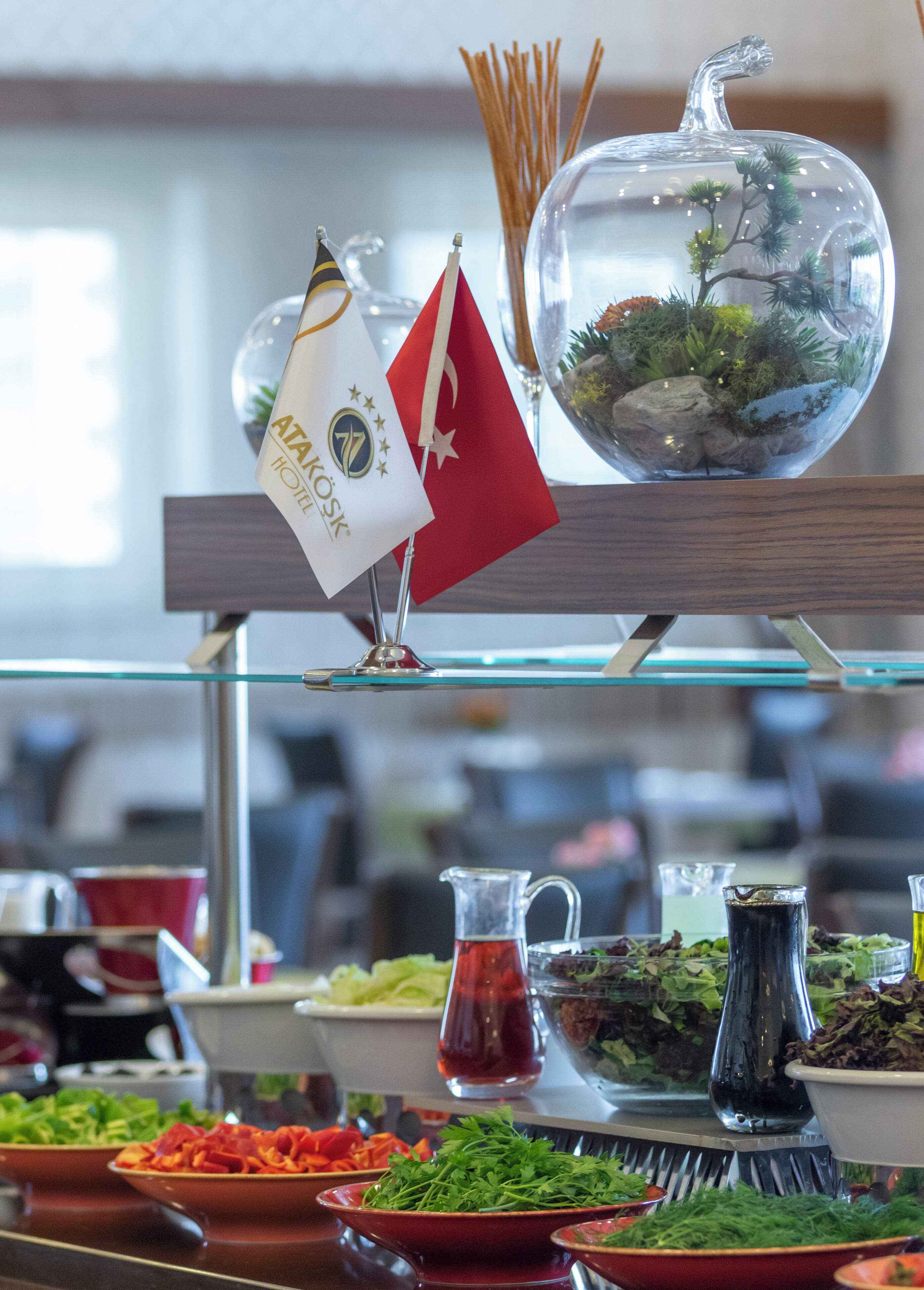 Un dispositiu de buffet amb diferents plats, una cúpula de vidre decorativa amb plantes, i banderes.