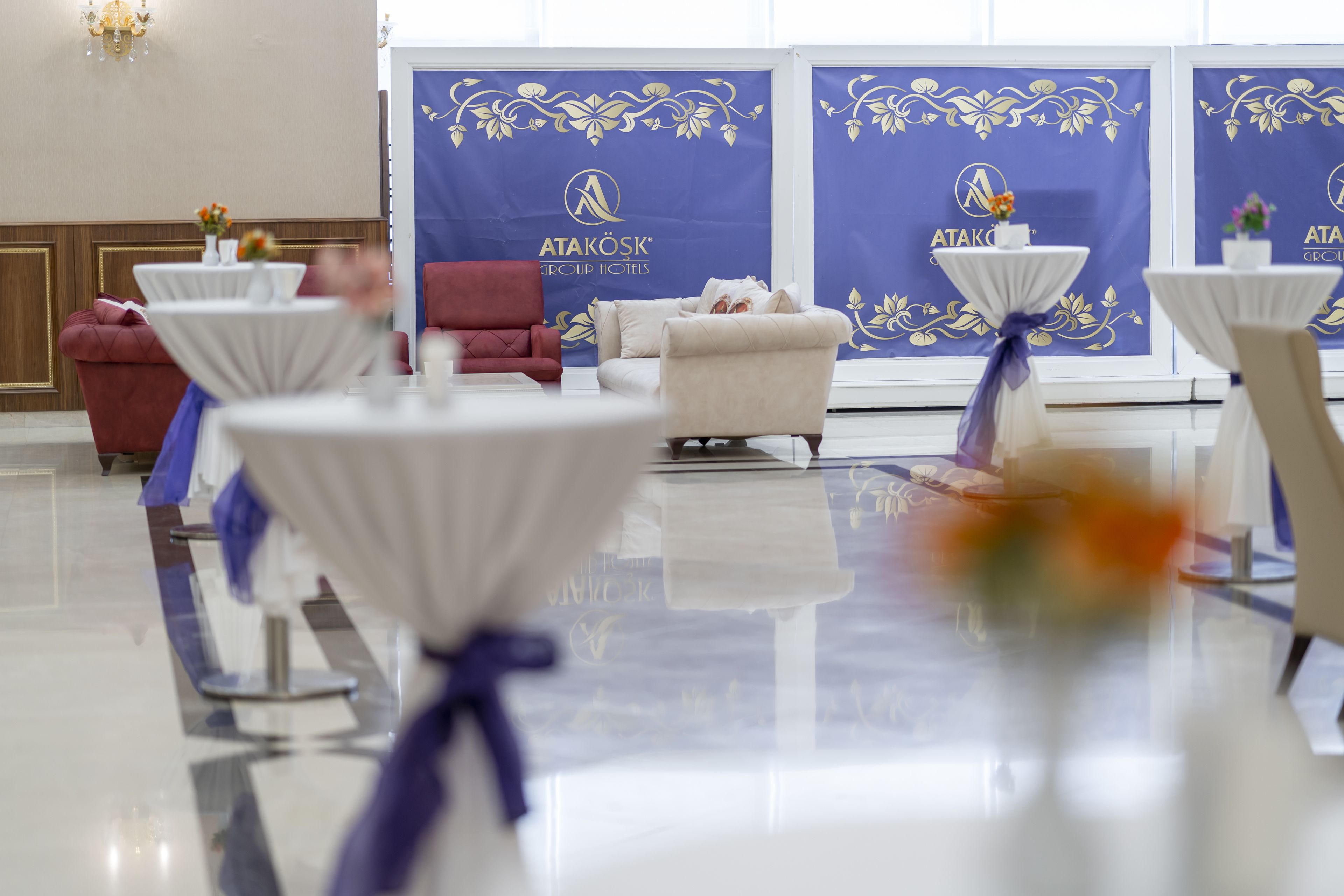 A hotel lobby with round tables, a red sofa, and a white armchair.