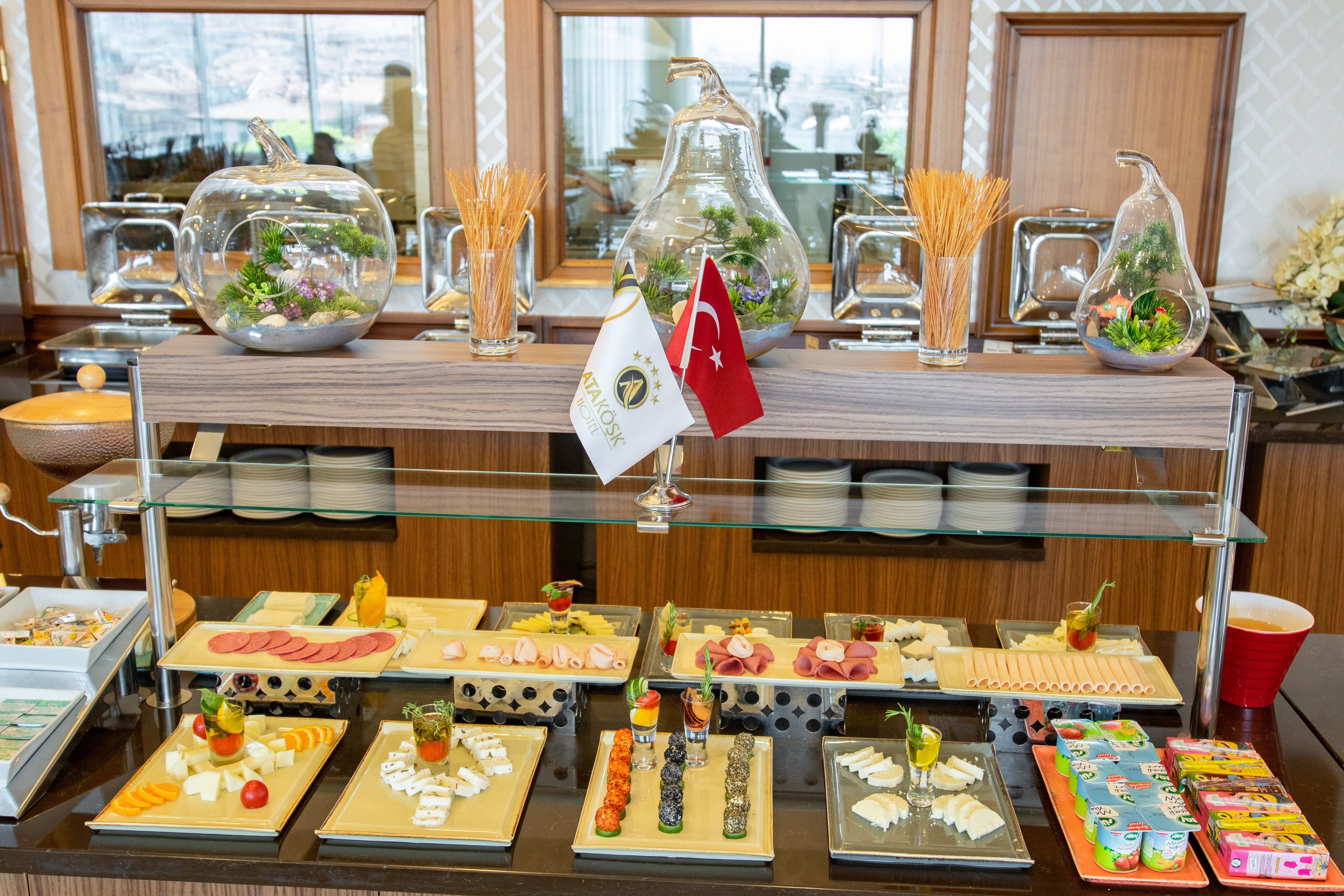 Un bufé con diversos alimentos y jarrones de vidrio decorativos.