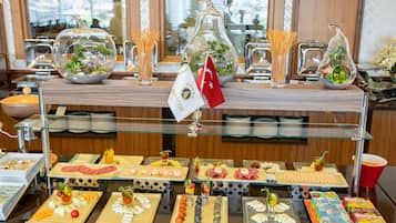 Un bufé con diversos alimentos y jarrones de vidrio decorativos.