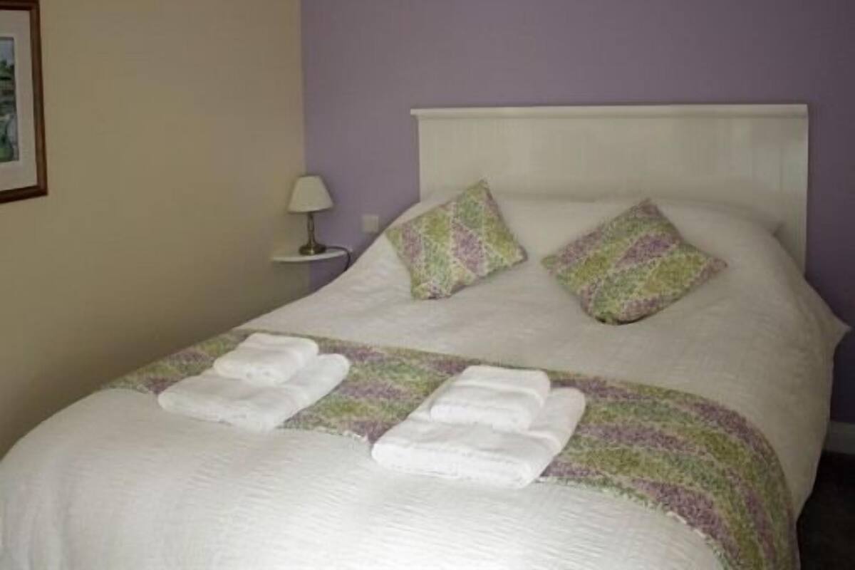 A neatly made bed with a white headboard, two decorative pillows, and two folded towels.