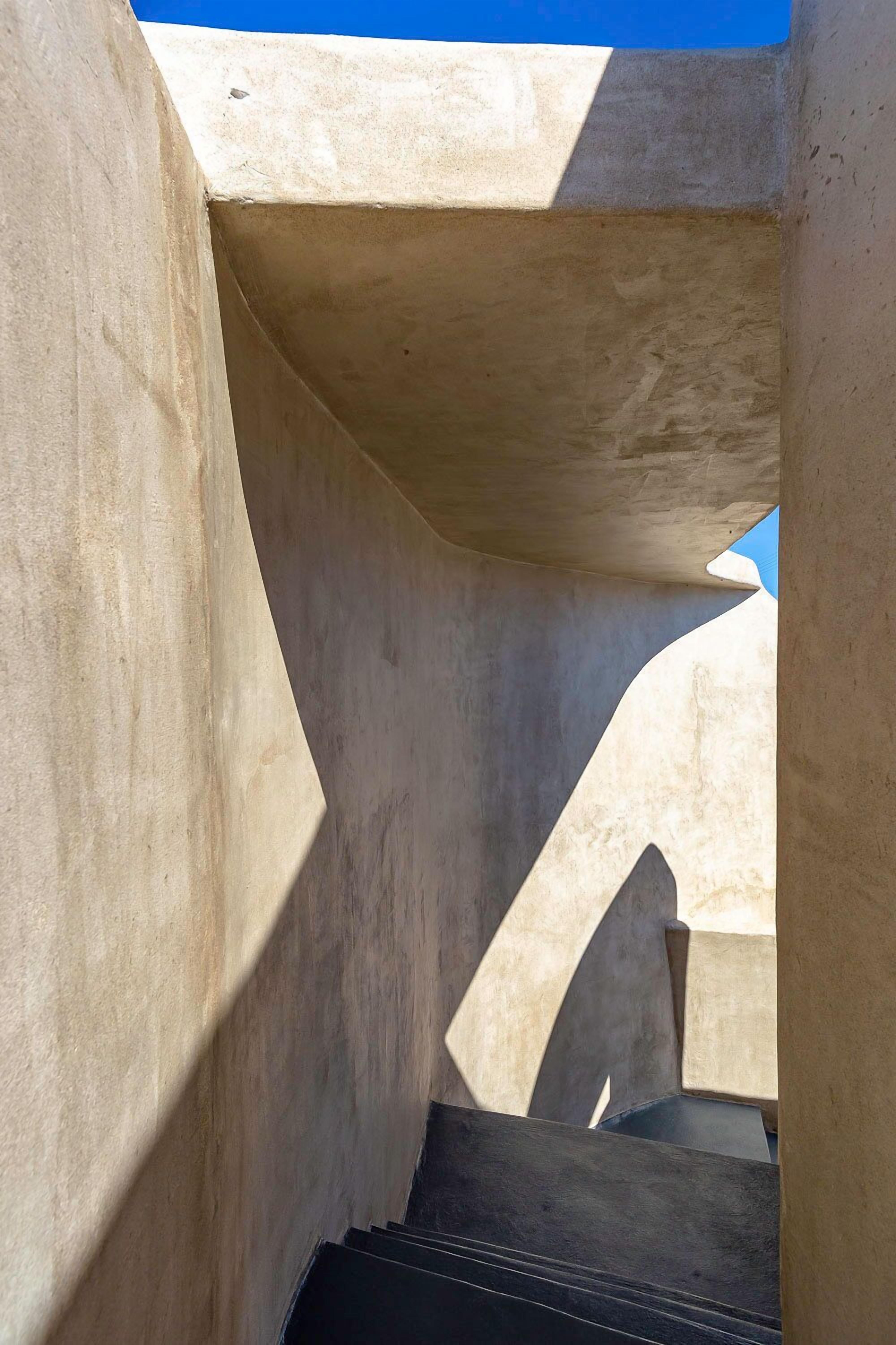 A concrete architectural structure with angular shapes and a clear blue sky in the background.