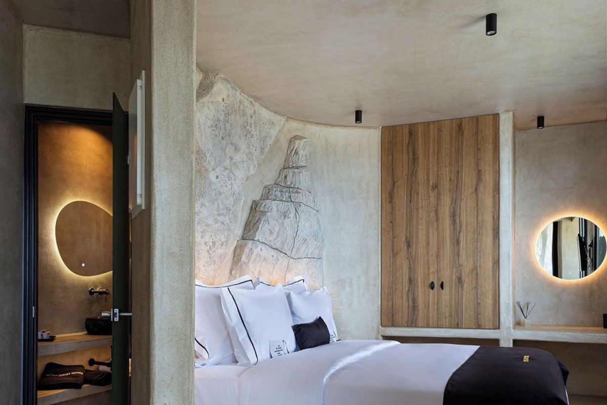 Quarto moderno com cama embutida, parede decorada com pedra, armário de madeira e espelho redondo.