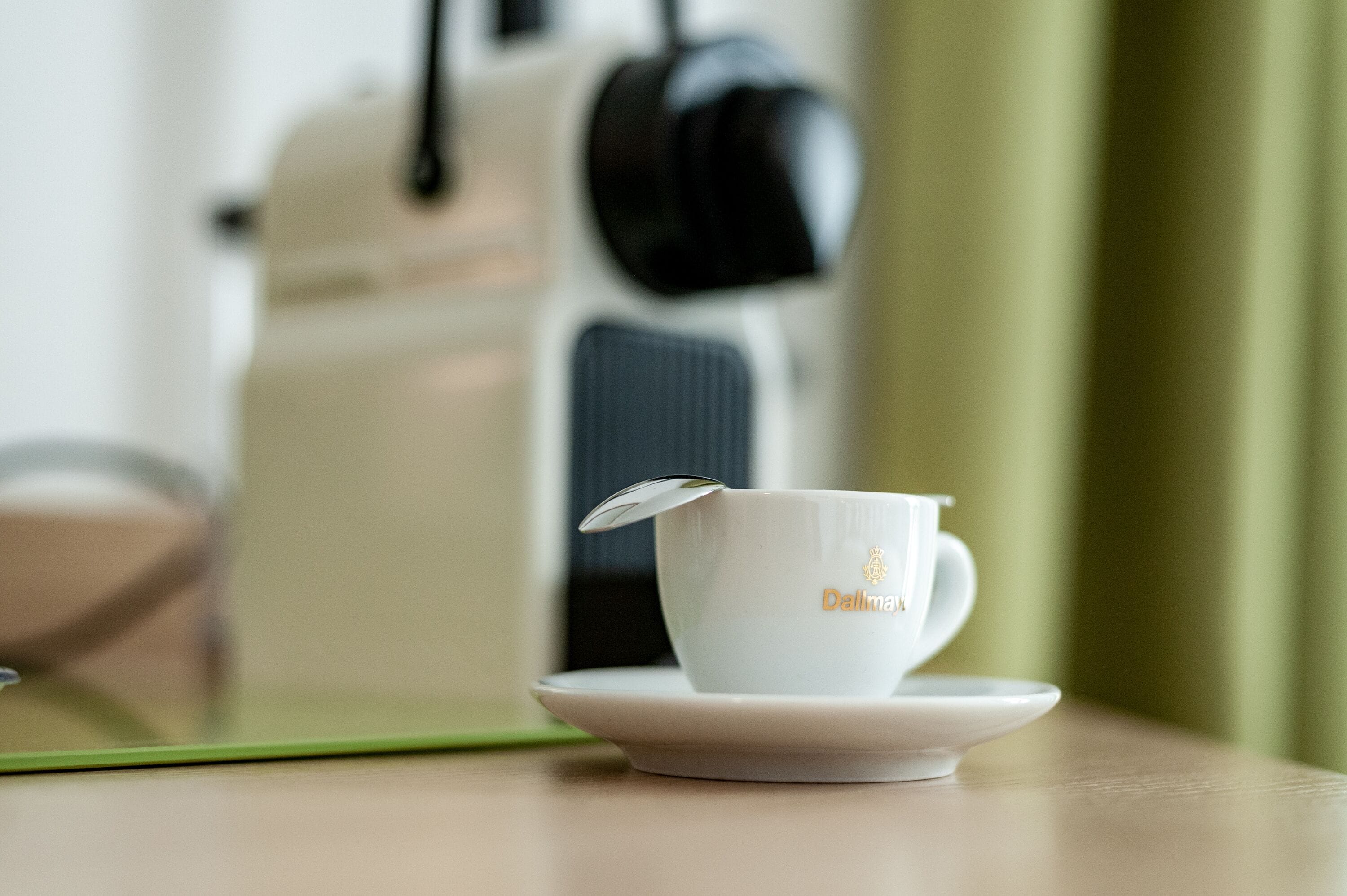 A white cup with a lid on a saucer, placed on a table with a green placemat.