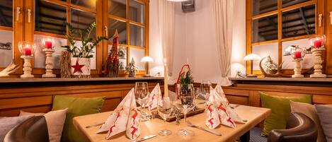 Comedor con una mesa dispuesta para cuatro personas, paredes con paneles de madera y una araña.