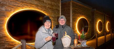 Deux personnes sont debout près d’une table, devant un verre, une bougie et un petit sapin de Noël.