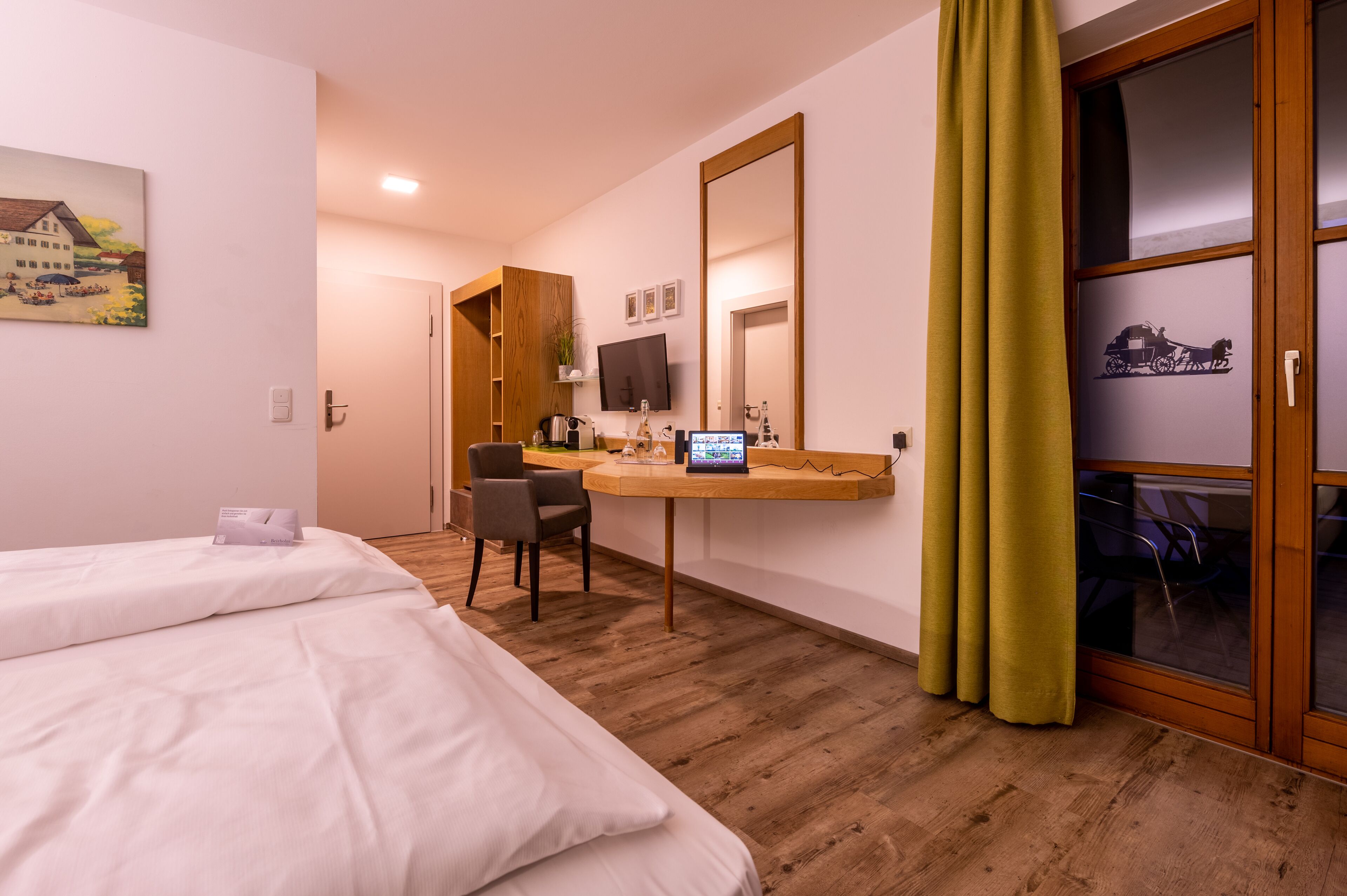 A hotel room with two beds, a desk with a computer, a TV, and a large mirror.