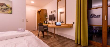 A hotel room with two beds, a desk with a computer, a TV, and a large mirror.