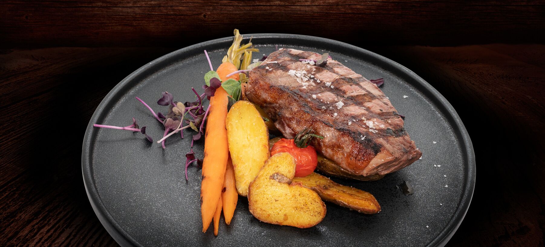 Un plato con carne, zanahorias y patatas.