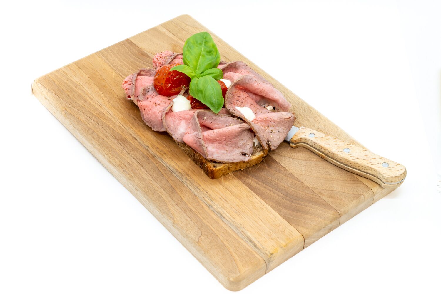 A slice of meat on a slice of bread with a knife on a wooden cutting board.