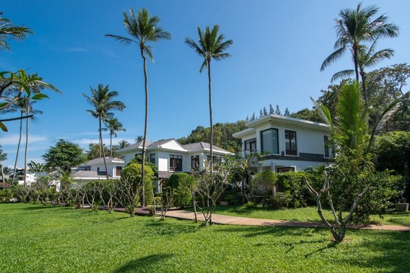 A residential area with two white houses, surrounded by well-maintained lawns and palm trees.