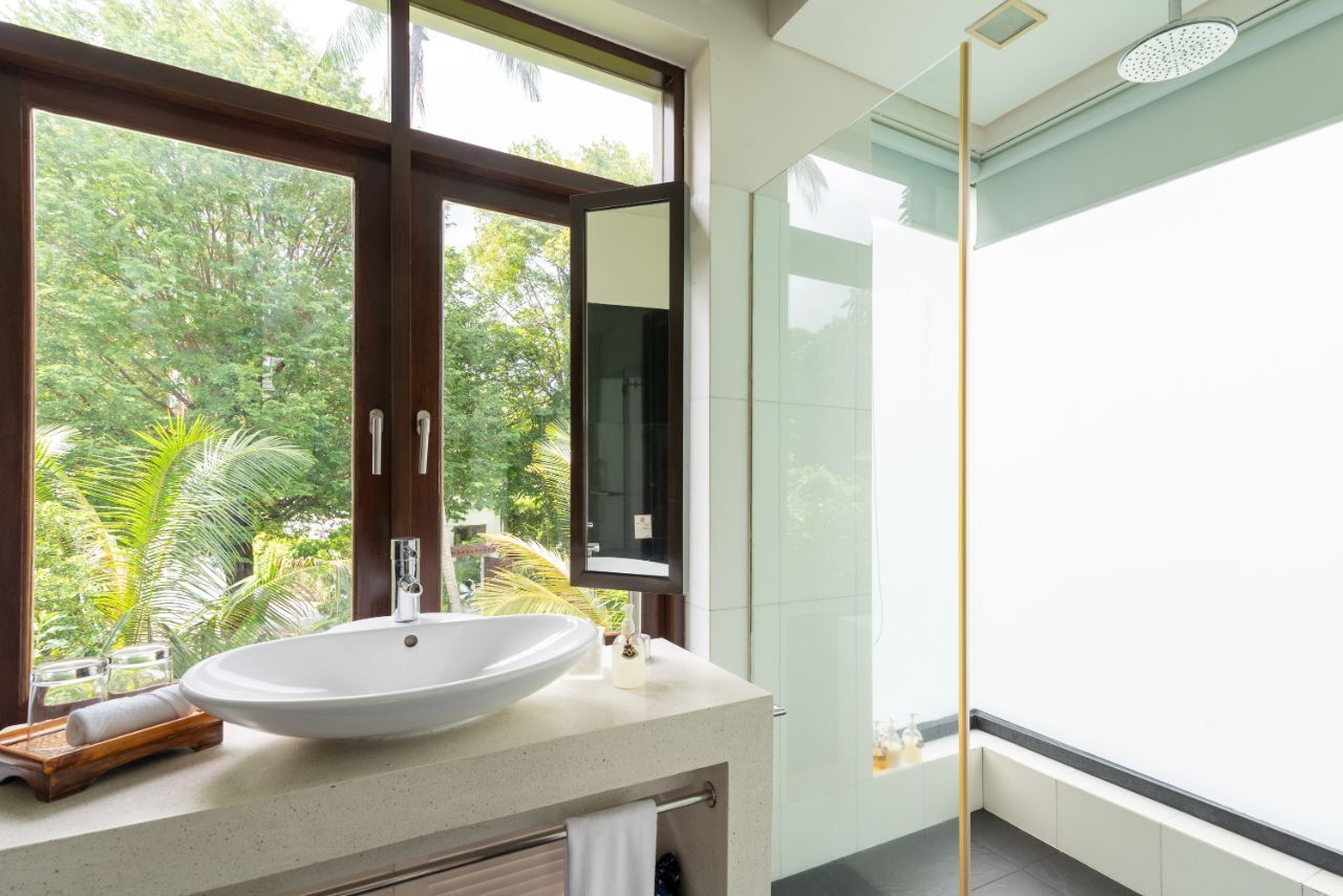 Ein modernes Badezimmer mit einem großen Waschbecken, einem Spiegel und einer Dusche.