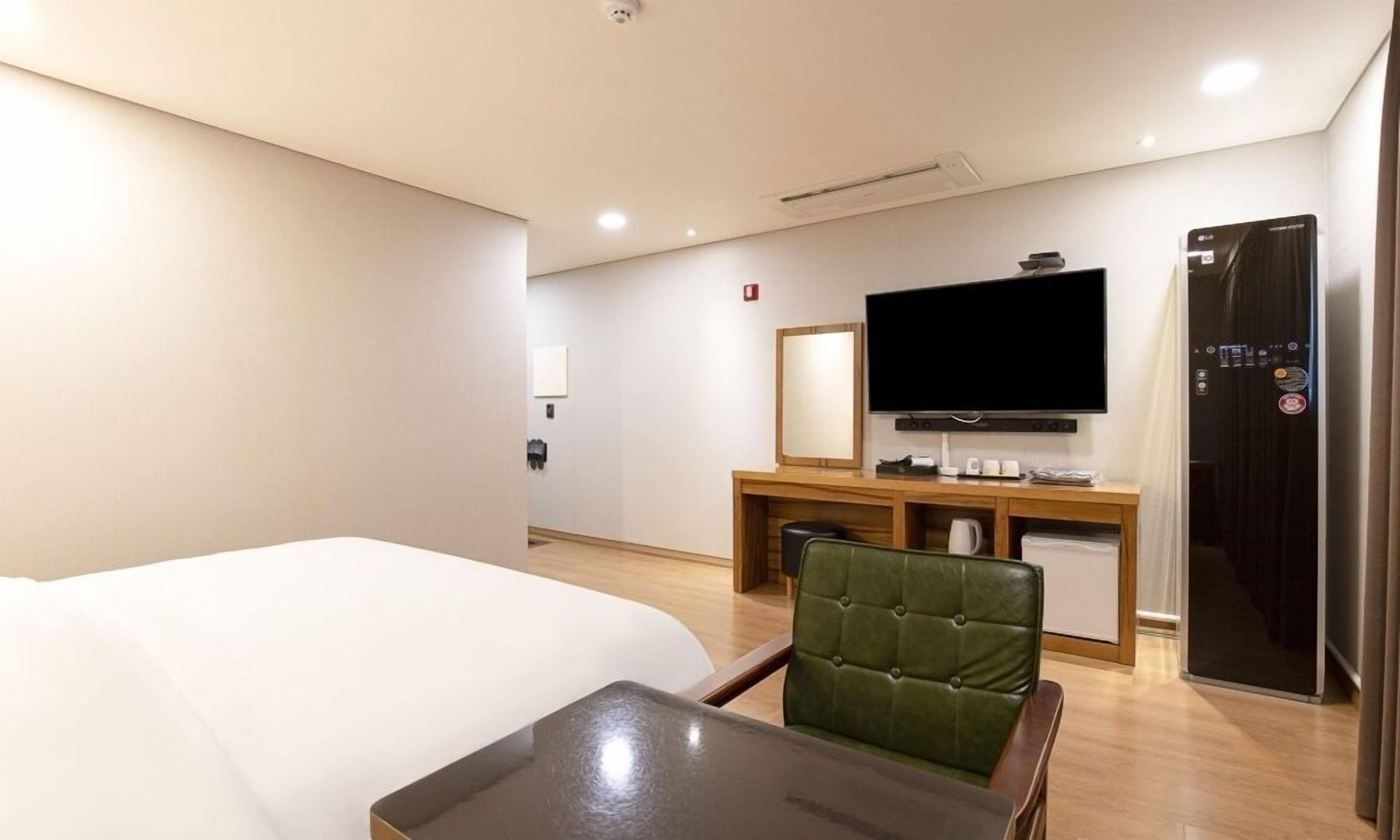 Ett hotellrum med en säng, en tv, ett skrivbord och en stol.