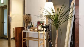 Un couloir avec une chaise en bois, une table ornée de divers objets décoratifs, une lampe et une plante en pot.