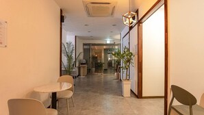 A hallway with a dining area featuring a round table and chairs, potted plants, and a staircase leading to another level. - Anyang CNC Hotel (Anyang)