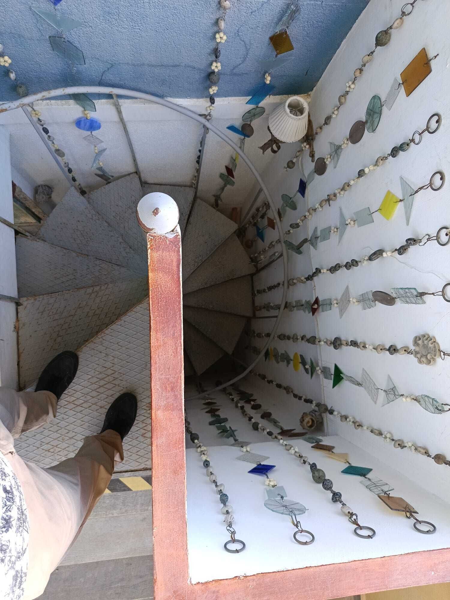 Un escalier en colimaçon doté d’une rampe et d’un mur orné de divers éléments décoratifs.