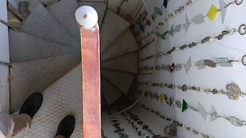 Una escalera de caracol con barandilla y un muro decorado con varios adornos.