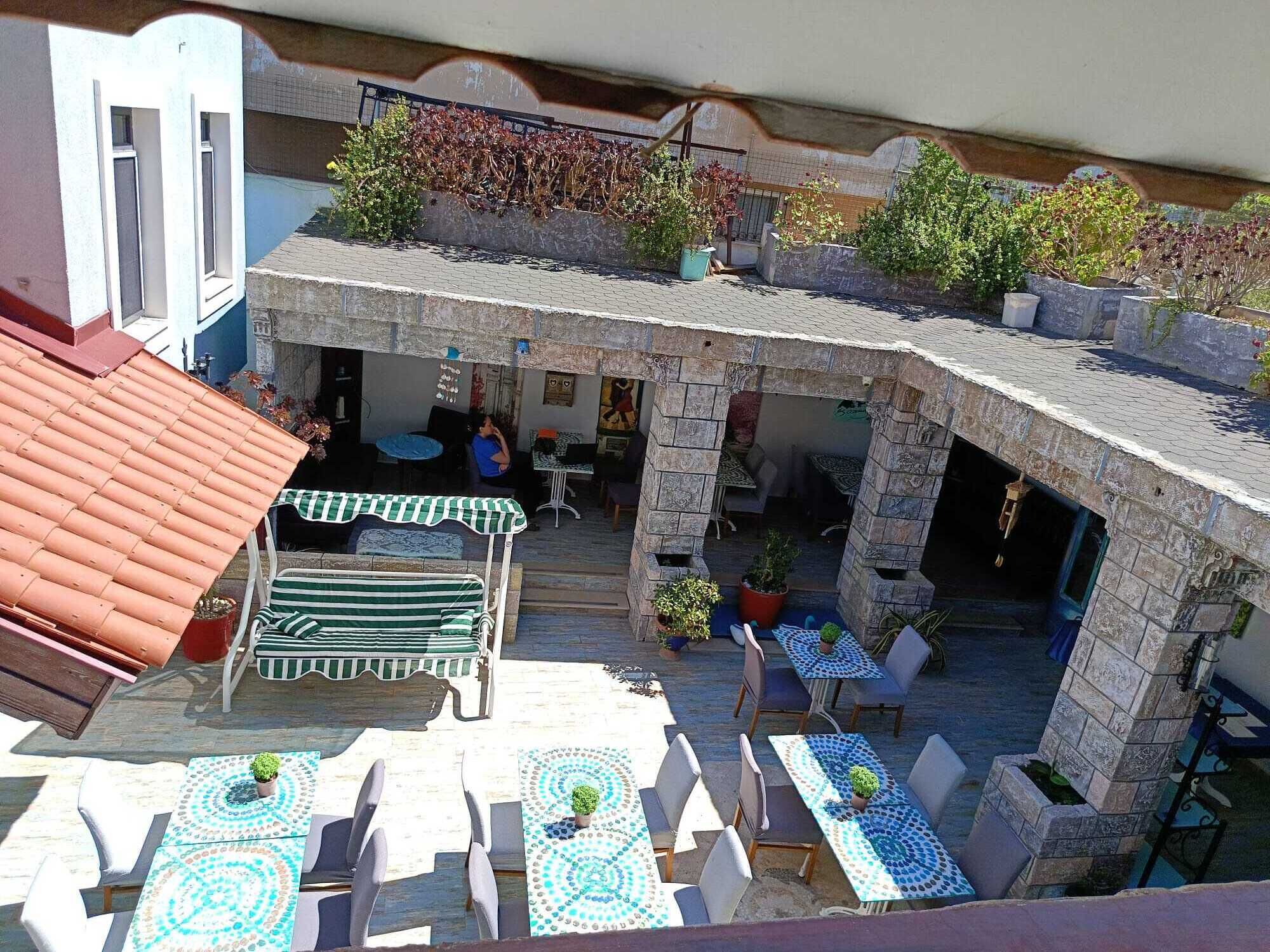 An outdoor patio with stone pillars, tables, chairs, and potted plants.