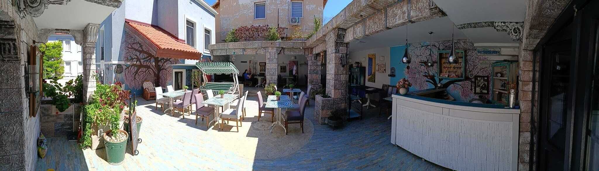 A narrow courtyard with outdoor seating, a stone wall, and a shop with various items displayed.