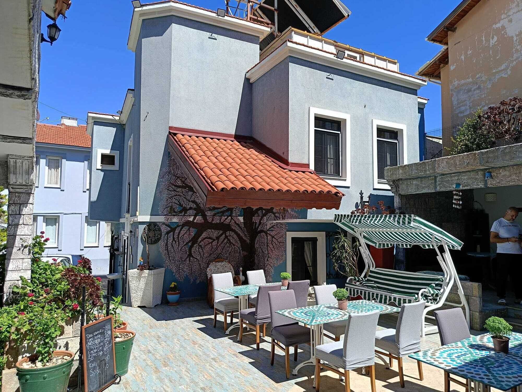 Un patio con asientos al aire libre, un mural y un edificio con techo de tejas rojas.