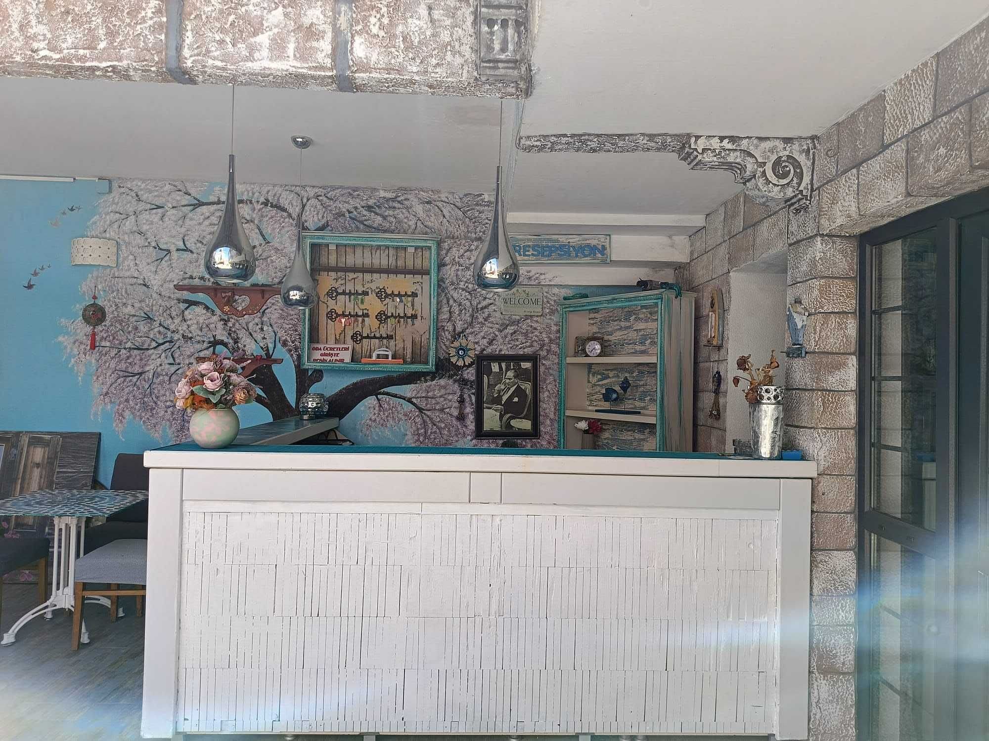 A reception desk with a 'WELCOME' sign, a wall mural, and a decorative shelf.