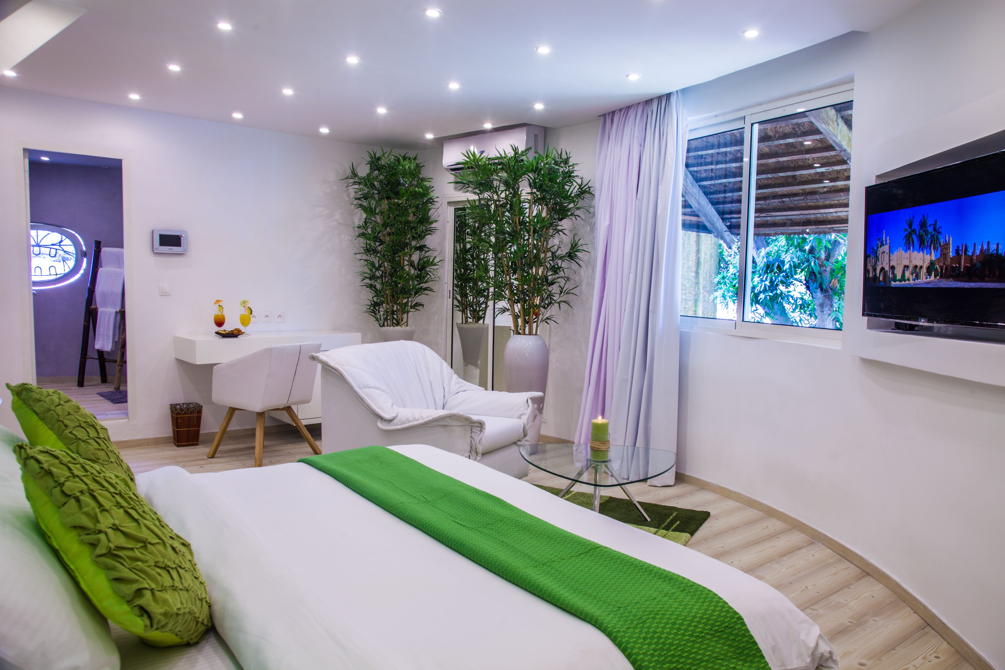 Una habitación de hotel moderna con cama, escritorio, silla, televisor y un amplio ventanal.