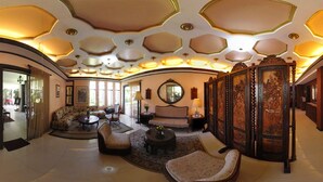 A spacious living room with a sofa, armchairs, a coffee table, and a decorative wooden screen.