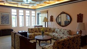 A living room with a sofa set, a coffee table, and a round mirror on the wall.