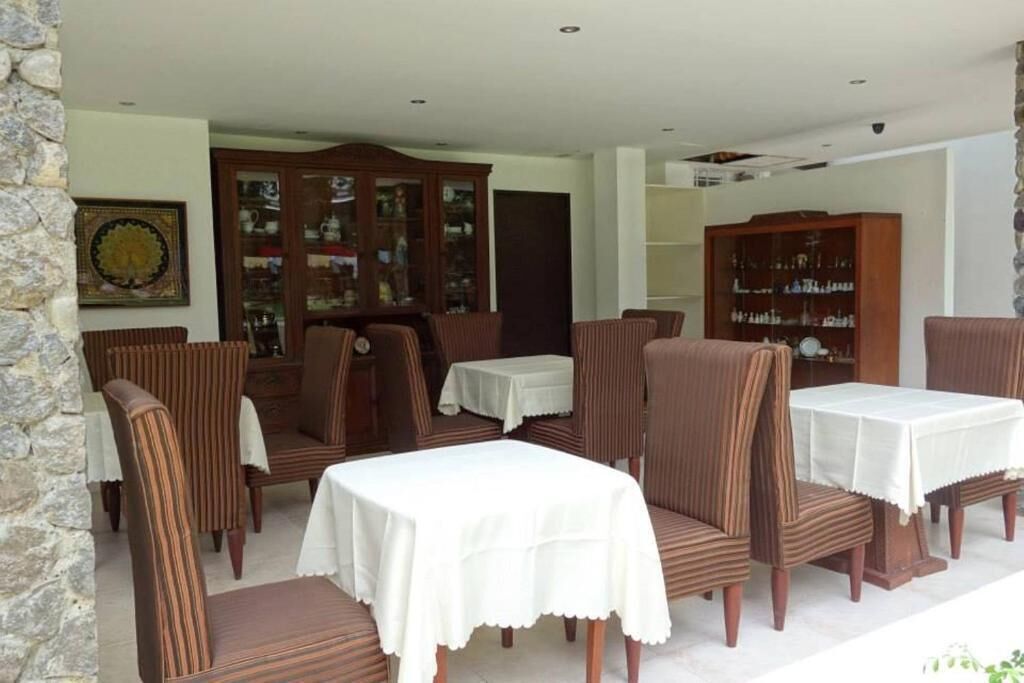 Un comedor con sillas y mesas a rayas, un aparador de madera con puertas de vidrio y una pared de piedra.