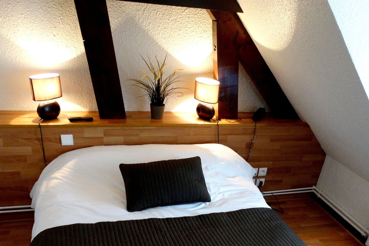 Une chambre à coucher avec une tête de lit en bois, une couvre-lit noire et deux lampes de chevet.