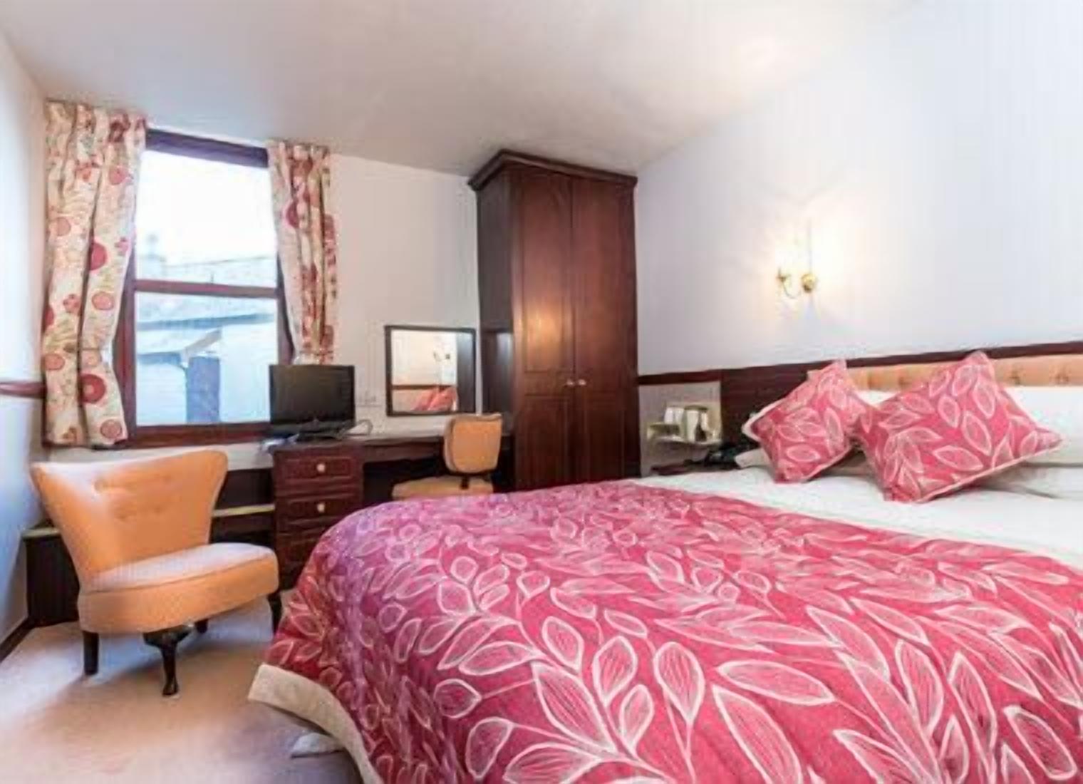 Ein Schlafzimmer mit einem großen Bett, einem Schreibtisch, einem Stuhl und einem Kleiderschrank.