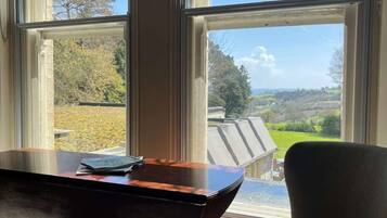 A room with a large window, a wooden table, and a chair.