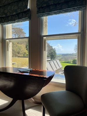 A room with a large window, a wooden table, and a chair. - Penmorvah Manor Hotel (Falmouth)
