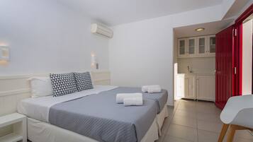 Una habitación de hotel con cama, mesitas de noche, escritorio y kitchenette.