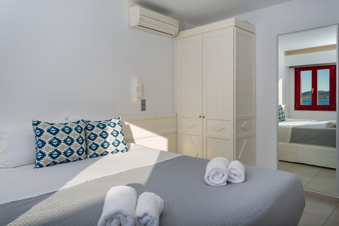 Een hotelkamer met een bed, een kledingkast, een spiegel en een raam met een rode omlijsting.