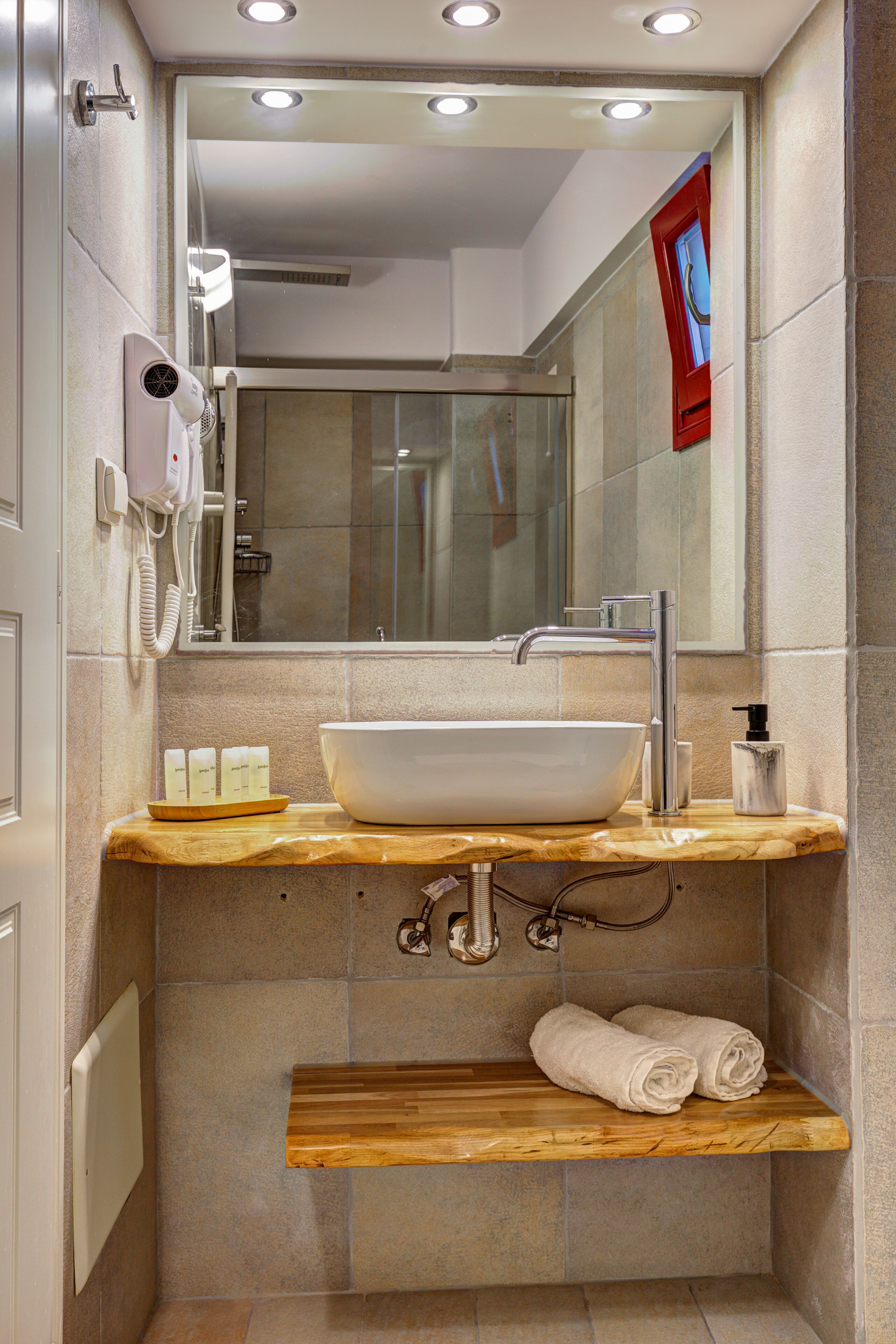 A bathroom with a white sink, a mirror, a hairdryer, and a towel rack.
