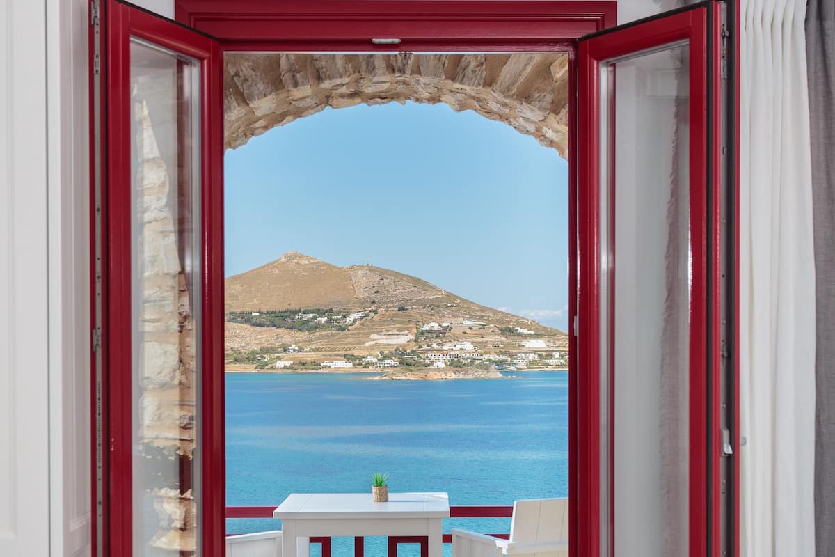 A room with a view of the sea and a mountain.