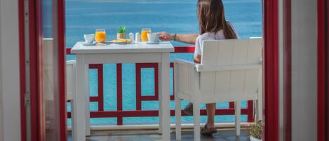 Eine Frau sitzt an einem Tisch mit Blick auf das Meer.