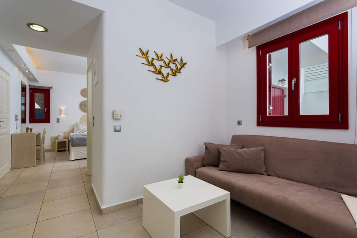 A modern living room with a beige sofa, a white coffee table, and a decorative wall piece.