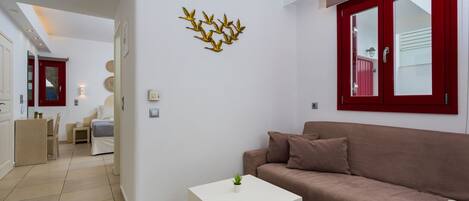 A modern living room with a beige sofa, a white coffee table, and a decorative wall piece.